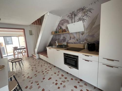 une cuisine avec des armoires blanches et une table et des chaises dans l'établissement Maison Terracotta des Karantes, à Narbonne-Plage