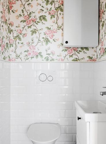 a bathroom with a white toilet and flowers on the wall at Lakefront house on Skåne's largest island in Ivö