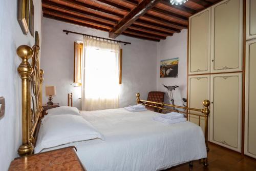 a bedroom with a bed with white sheets and a window at Tipica casa nelle Crete Senesi in Monteroni dʼArbia