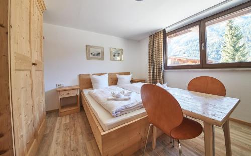 a bedroom with a bed and a table and a window at Appartement Kohlmais in Saalbach Hinterglemm