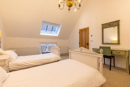 a bedroom with two beds and a desk and a mirror at Swafield Hall in Swafield