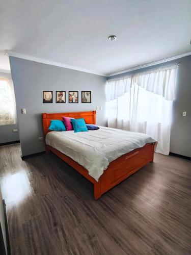 ein Schlafzimmer mit einem großen Bett mit blauen und rosa Kissen in der Unterkunft Hermosa Casa Vacacional o de Hospedaje en Cuenca in Cuenca