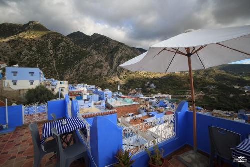 a balcony with an umbrella and blue and white buildings at Casa Sanae in Chefchaouene