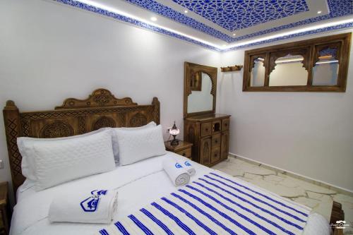 a bedroom with a large bed with a blue ceiling at Casa Sanae in Chefchaouene