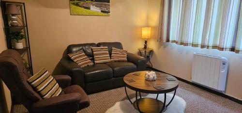 a living room with a leather couch and a table at Ash Cottage in Stranraer