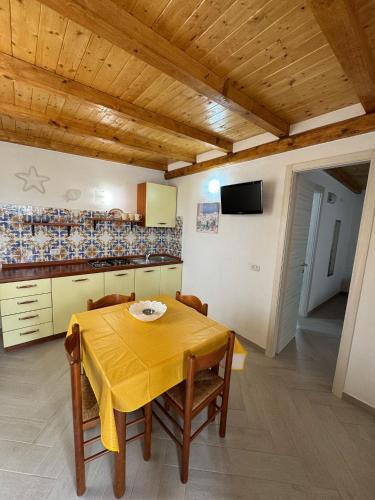 a kitchen and dining room with a yellow table and chairs at Villa Ninfa in Lampedusa