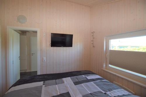 a bedroom with a bed and a television on the wall at Ferienhaus Nordseeluft in Wesselburenerkoog