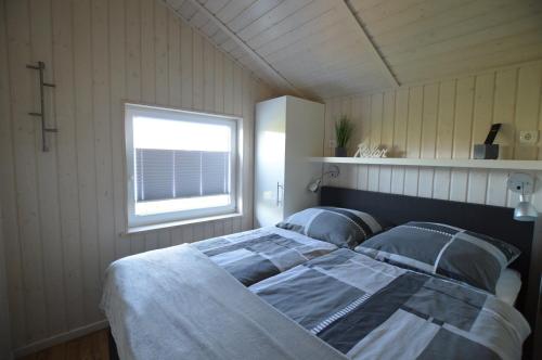 a bedroom with a large bed with a window at Ferienhaus Nordseelicht in Wesselburenerkoog