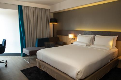 a hotel room with a large bed and a chair at Novotel London Wembley in London