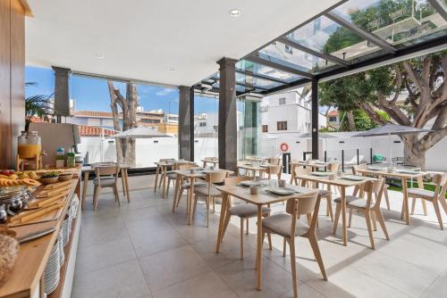 a restaurant with tables and chairs and windows at Las Dunas de Santa Catalina Boutique House in Las Palmas de Gran Canaria
