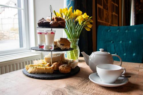 a table with a tray of pastries and a cup of coffee at Hotel Plas Hyfryd in Narberth