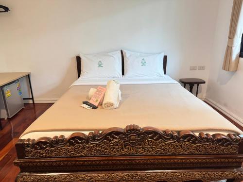 a bed with two towels and a book on it at Collection O Khu Mueang near Tha Phae Gate formerly Lai Thai Guesthouse in Chiang Mai