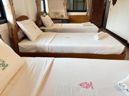 two beds in a room with white sheets at Collection O Khu Mueang near Tha Phae Gate formerly Lai Thai Guesthouse in Chiang Mai