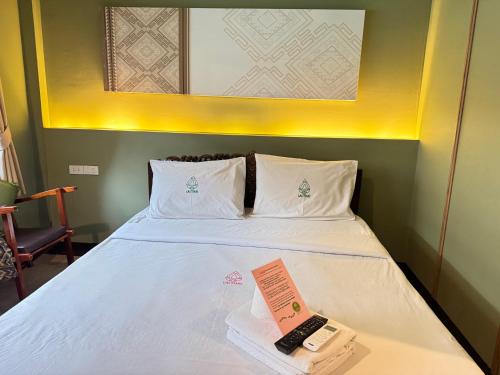 a hotel room with a bed with a remote control on it at Collection O Khu Mueang near Tha Phae Gate formerly Lai Thai Guesthouse in Chiang Mai