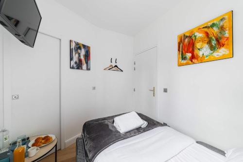 Cette chambre blanche dispose d'un lit et d'une peinture murale. dans l'établissement Studio cosy metro pereire paris 17 - 2P, à Paris