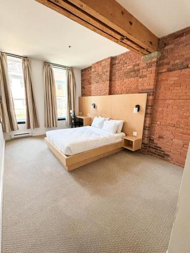 a bedroom with a large bed in a brick wall at Queen Room at The Franklin Hotel Downtown on Water Street in St. John's