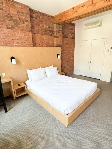 a large bed in a room with a brick wall at Queen Room at The Franklin Hotel Downtown on Water Street in St. John's