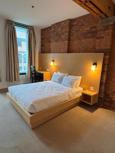a bedroom with a large bed with a brick wall at Queen Room at The Franklin Hotel Downtown on Water Street in St. John's
