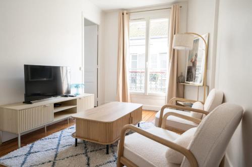 un salon avec une table et une télévision dans l'établissement Appartement voltaire refait a neuf - 2P paris 11, à Paris