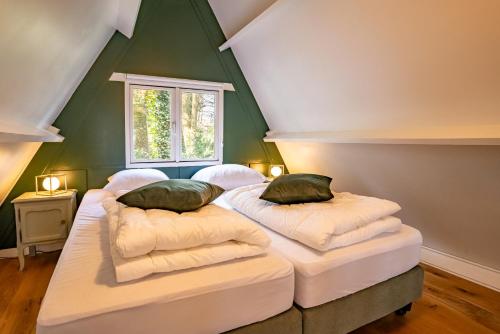 two beds in a room with a green wall at Boshuisje Rekem - Ignis in Lanaken