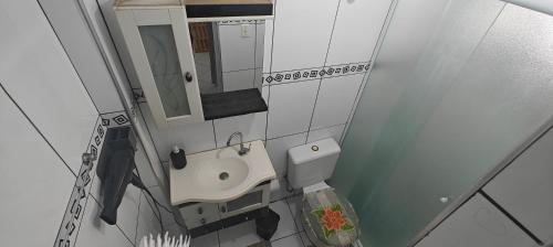 a small bathroom with a sink and a mirror at Refúgio Santista - Seu lar com vaga no litoral in Santos