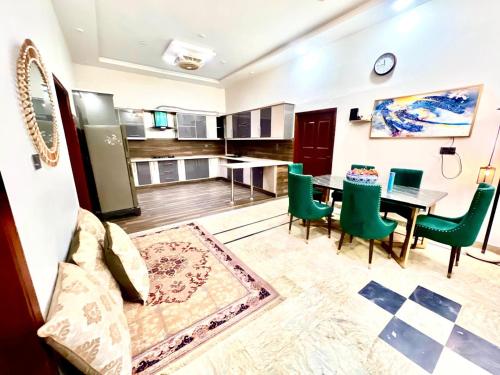 a living room with a table and green chairs at BNB Royal Inn Family-Stadium-karsaz-Airport in Karachi