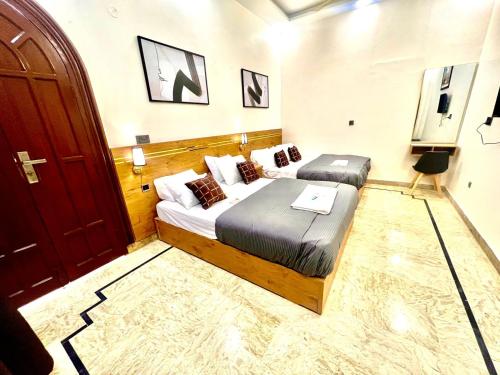 a hotel room with two beds and a door at BNB Royal Inn Family-Stadium-karsaz-Airport in Karachi