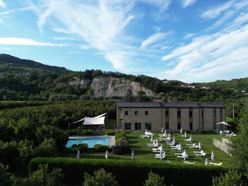 a building with a bunch of white chairs and a pool at Agriresort Villa Gelso- Adults Friendly in Vesime