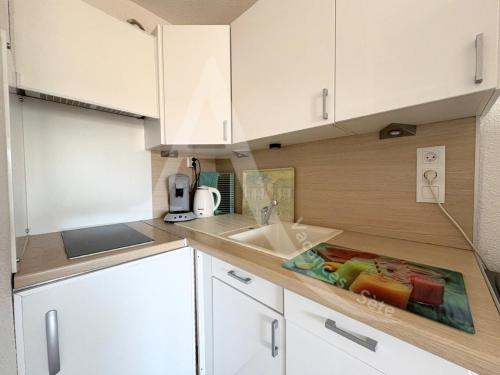 une cuisine avec des armoires blanches et un évier dans l'établissement T2 avec garage, quartier Corniche proche des plages, à Sète