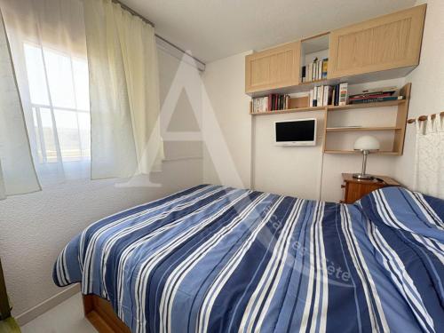 - une chambre avec un lit bleu et blanc et une fenêtre dans l'établissement T2 avec garage, quartier Corniche proche des plages, à Sète