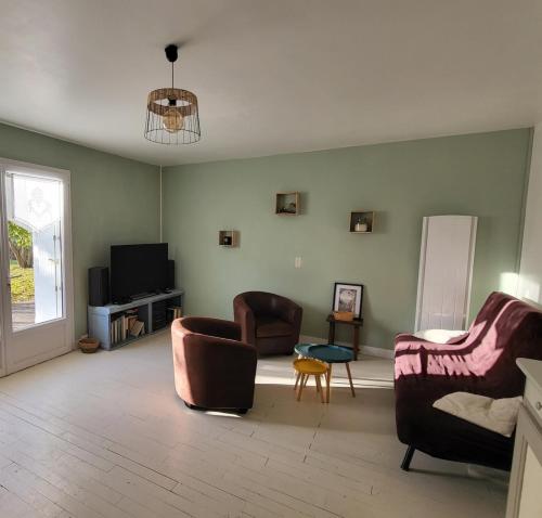 un salon avec deux canapés et une télévision dans l'établissement Maison à la campagne pour escapades touristiques !, à Nalliers