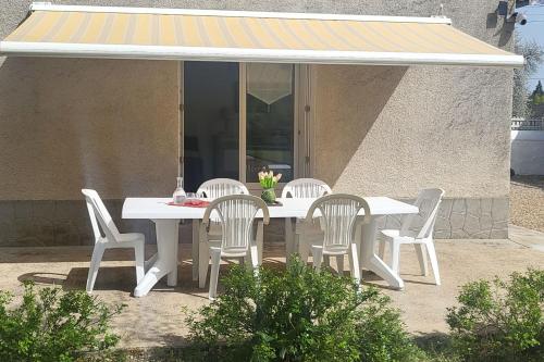 une table blanche et des chaises sur une terrasse dans l'établissement Maison à la campagne pour escapades touristiques !, à Nalliers