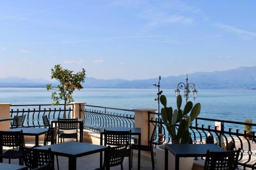a patio with tables and chairs and a view of the water at La Vista Postcard Hotel in Lazise