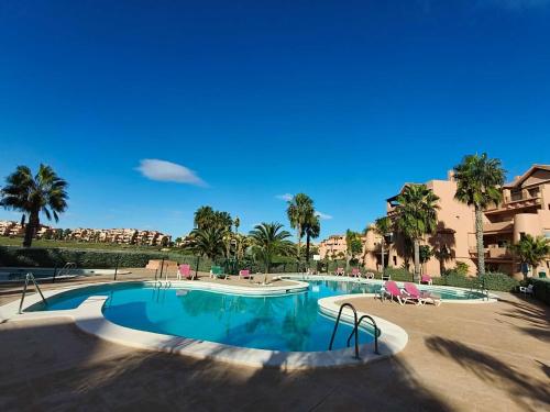 a large swimming pool with palm trees and buildings at Mar Menor Golf Resort, Fitnes, Tennis, wellness, Security! in Torre-Pacheco