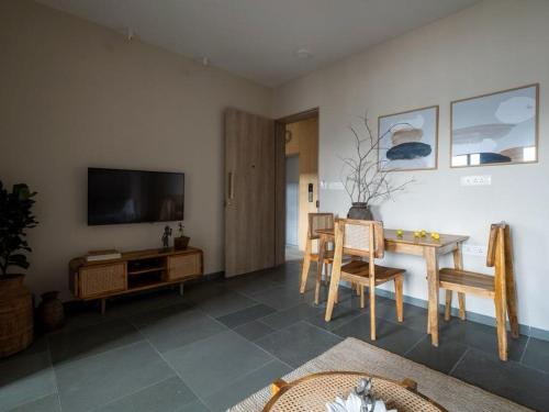 a living room with a television and a table and chairs at Hotel Tattva Suites in Pune