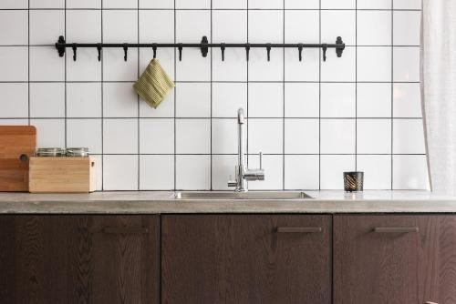 a kitchen with a sink and white tiled walls at Luxurious apartment for the modern executive in Luleå