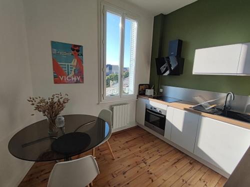 une cuisine avec une table et une salle à manger dans l'établissement Appartement lumineux refait à neuf, cœur de ville, à Vichy
