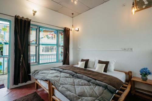 a bedroom with a bed and a large window at The Hood in Bīr