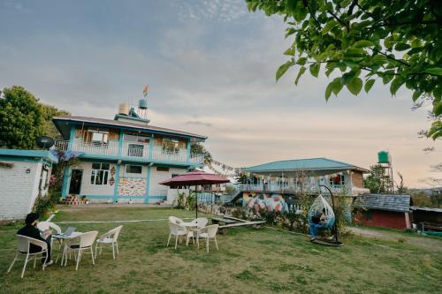 a group of people sitting in chairs in front of a house at The Hood in Bīr