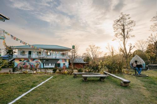 a woman standing in front of a house with a bench at The Hood in Bīr