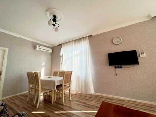 a dining room with a table and chairs and a tv at Soft Villa in Gabala