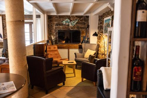 a living room with chairs and a tv at Hotel Puerto Arnela in Camariñas