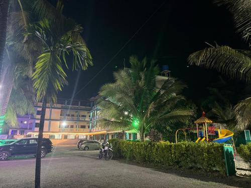 a parking lot with palm trees at night at Atithi farmhouse in Alibaug