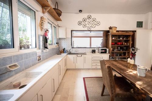 a kitchen with white cabinets and a wooden table at Bellavista at Heraion Lagoon in Loutraki