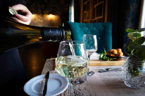 a person pouring white wine into a glass on a table at Hotel Plas Hyfryd in Narberth