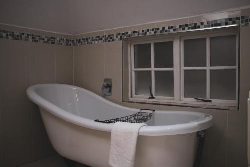 a white bath tub in a bathroom with a window at Rawdons Hotel & Brewery in Nottingham Road