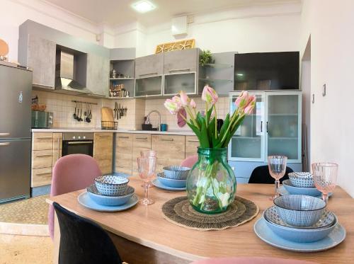 ein Esstisch mit einer Vase mit Blumen darauf in der Unterkunft Two Bedroom Apartment - Alexandrovska - Top Location - Central Bus, Train and Marine Stations, next to Sea Garden and Beach in Burgas City