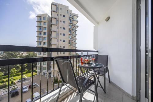 a balcony with a table and chairs and a building at Marathon Beach Apartment - Sea View, Shared Pool in Limassol