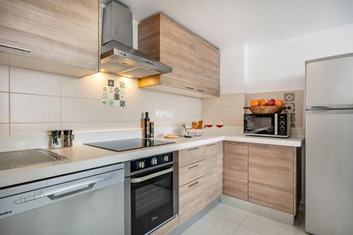 a kitchen with wooden cabinets and stainless steel appliances at Marathon Beach Apartment - Sea View, Shared Pool in Limassol