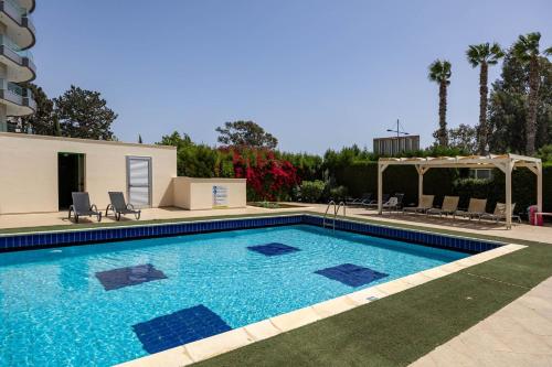 a swimming pool with blue water in a yard at Marathon Beach Apartment - Sea View, Shared Pool in Limassol